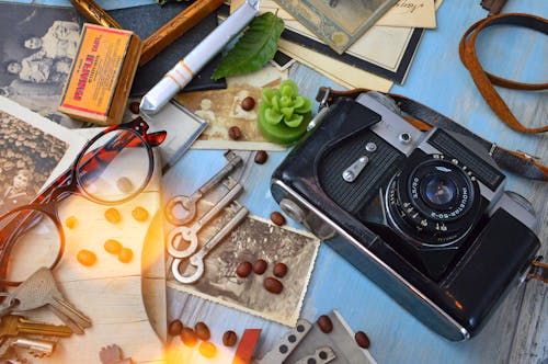 Black and Gray Dslr Camera Beside Three Gray Skeleton Keys