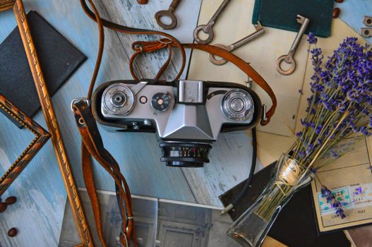 A vintage camera surrounded by lavender and keys on a wooden table flat lay.