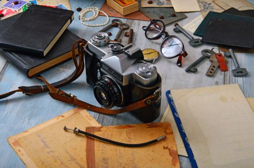 Free Explore a collection of vintage items, including a classic camera, keys, and books, set on an antique desk. Stock Photo