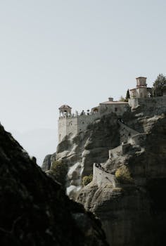Stunning view of a Meteora monastery set atop towering cliffs in Greece against a clear sky.
