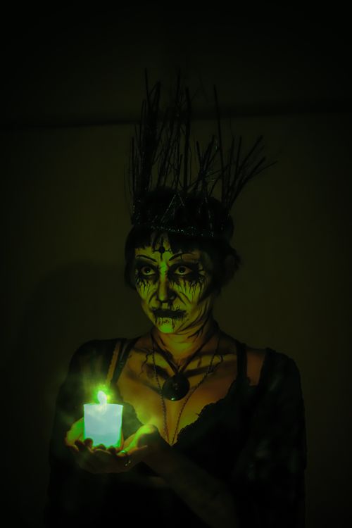 Free Dark and mysterious portrait of a woman in Halloween makeup holding a glowing candle. Stock Photo