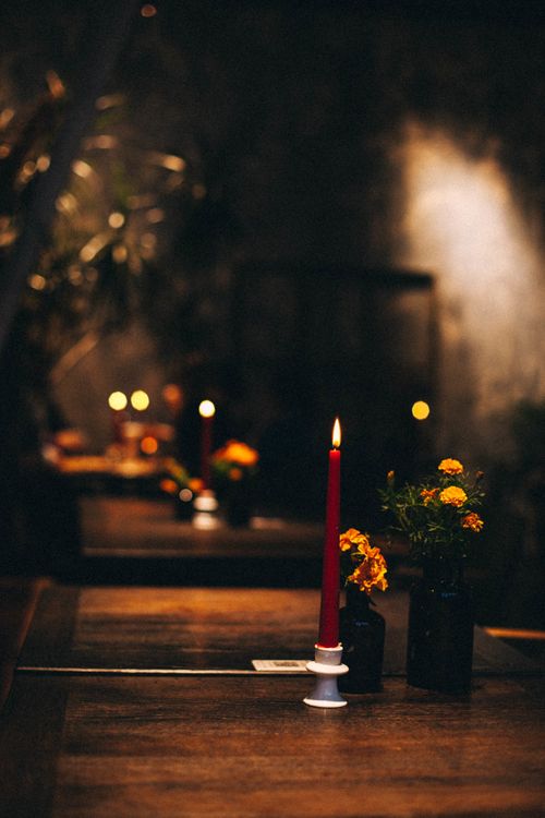 Free A romantic red candle burning on a cozy wooden table setting with dim lighting, creating a warm ambiance. Stock Photo