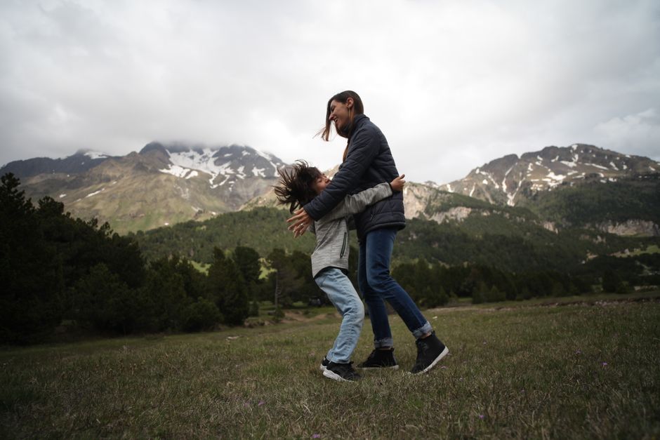 Mother and child sharing a warm embrace in the scenic Swiss mountains.