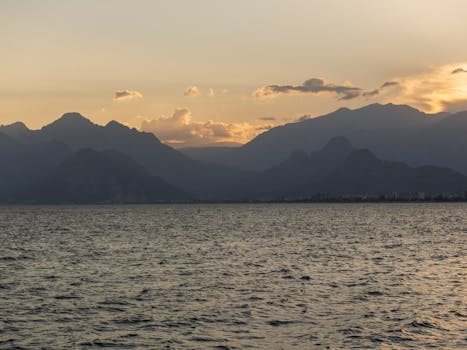 Dramatic ocean view with silhouettes of mountains at sunset, capturing golden hour beauty.