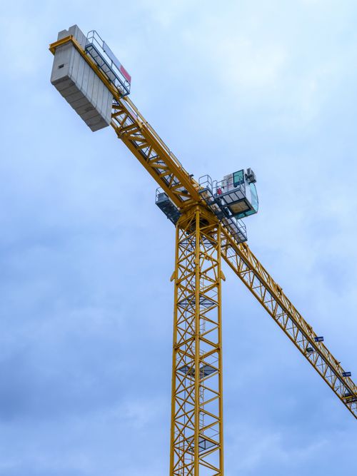 Free Yellow tower crane with metal structure against a cloudy blue sky. Stock Photo