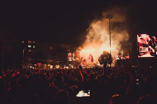 무료 밤 시간에 사람들 앞에서 연기가 자욱한 무대에서 공연하는 밴드 스톡 사진