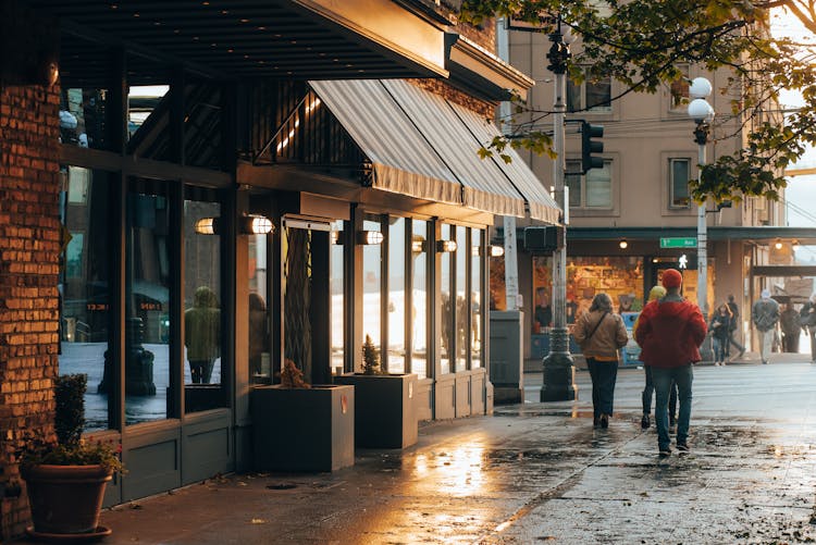 People Walking In Front Of Glass Building