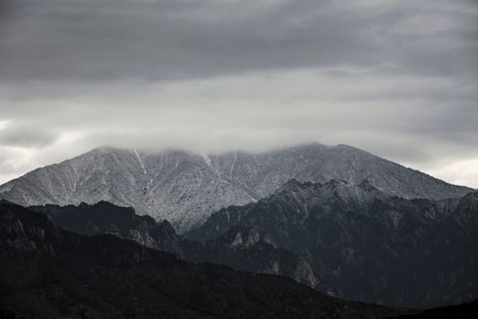 A majestic view of a rocky mountain range with dark clouds above, highlighting nature's dramatic scenery.