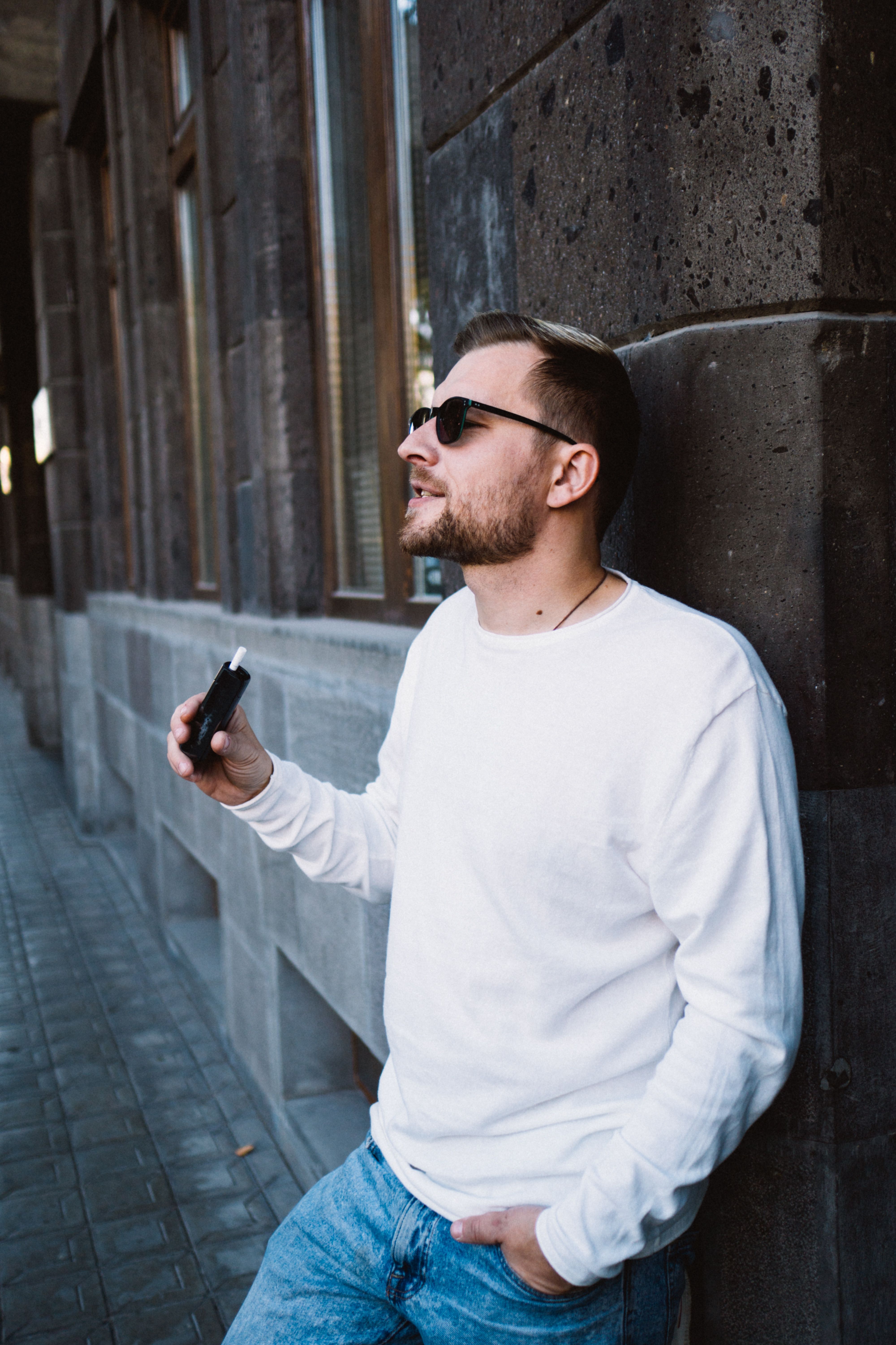 A Bearded Man Wearing Sunglasses Leaning on the Wall · Free Stock Photo