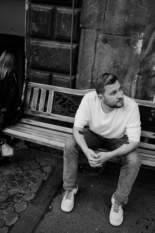 Grayscale Photo of a Man on a Wooden Bench 