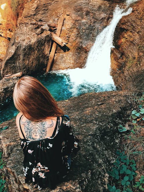 Woman Sitting on Rock on Top of Waterfalls