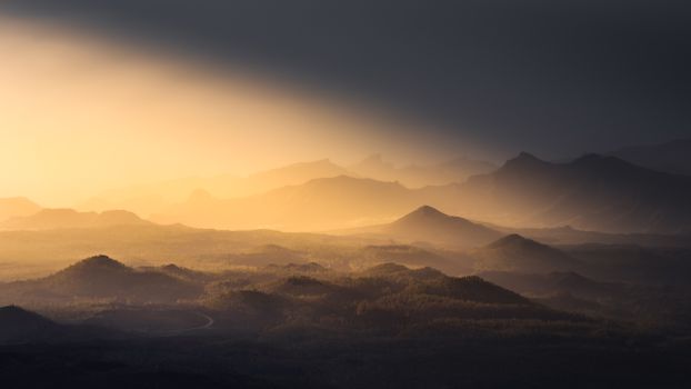 Stunning landscape of mountains silhouetted in the warm glow of sunset creating layers of dramatic tones.