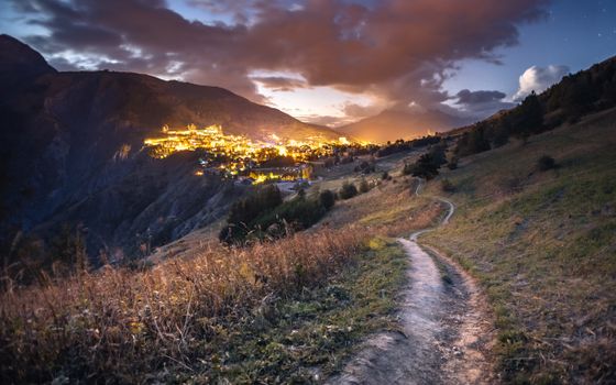 Stunning night view of a French alpine village with brightly lit buildings under a star-filled sky.