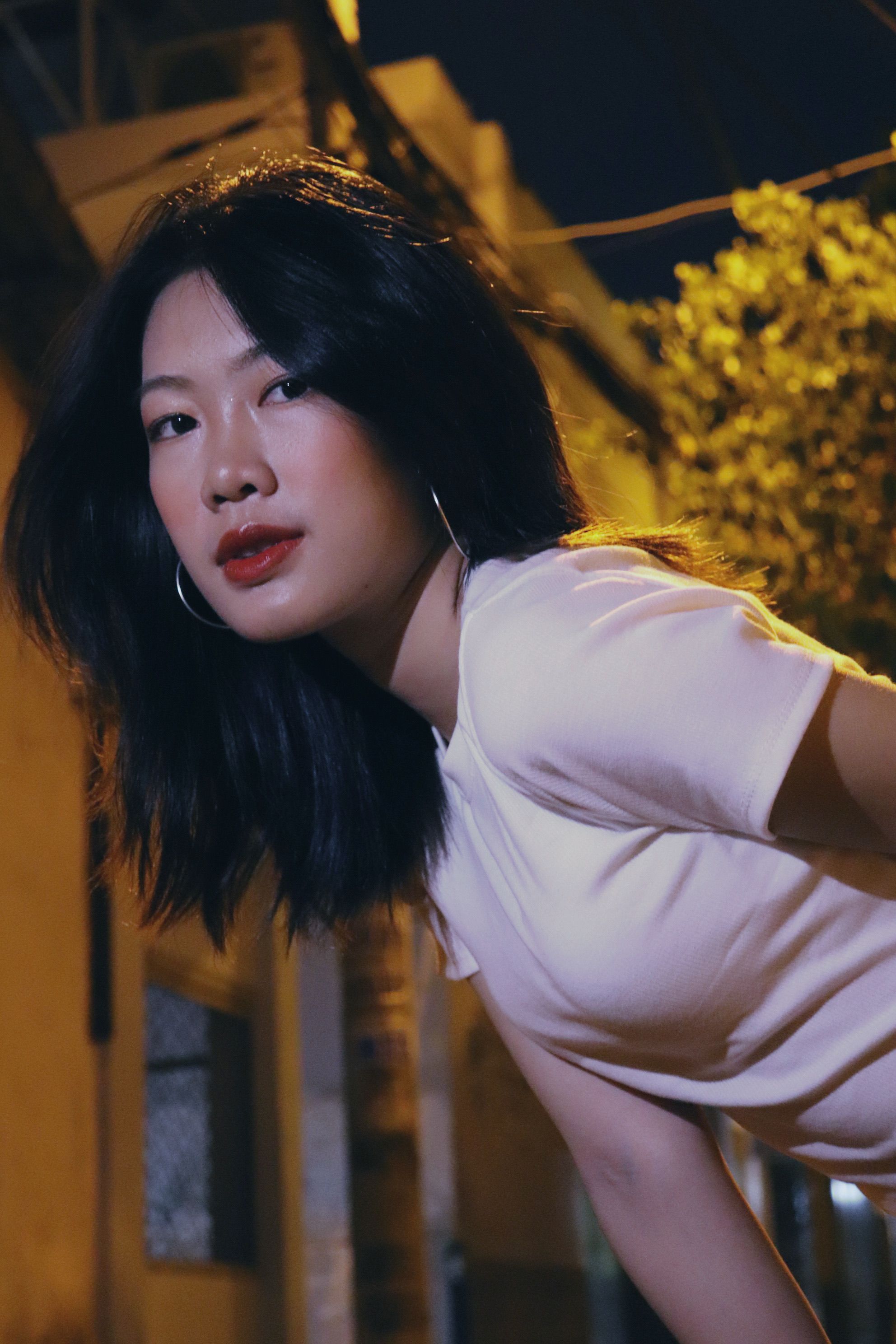 Elegant portrait of a woman with red lips at night in Ho Chi Minh City, Vietnam.