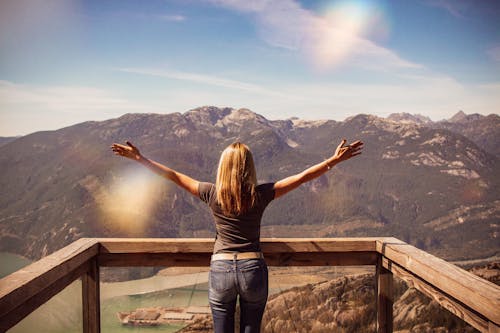 Free Woman Facing Mountains Raising Her Hands Stock Photo