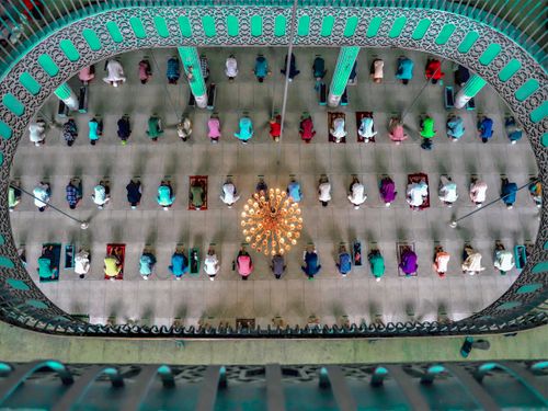 Free Top view of worshippers praying inside a beautifully designed mosque with chandelier and intricate architecture. Stock Photo