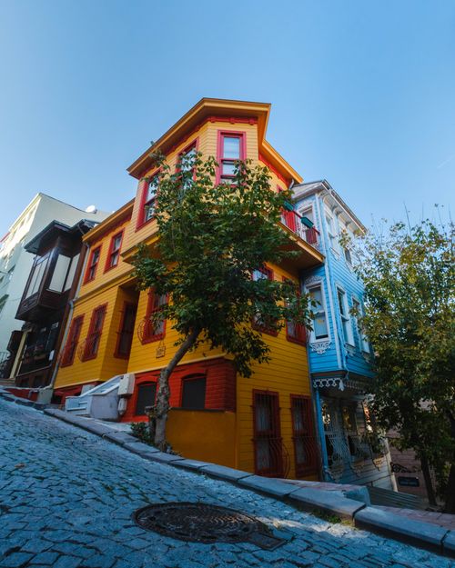Free Charming colorful houses line a steep cobblestone street under a clear sky, creating a vibrant urban scene. Stock Photo