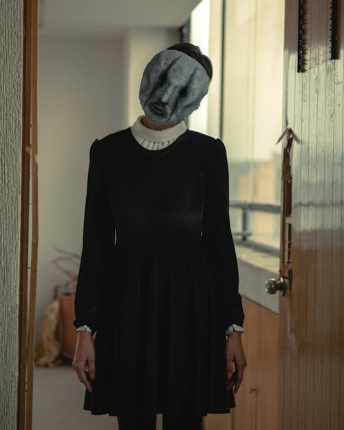 A Woman in Black Dress Standing on the Doorway Wearing a Scary Mask