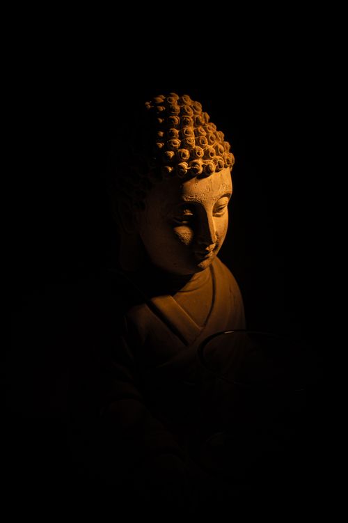 Free A serene Buddha sculpture illuminated by soft light against a dark background, exuding peace. Stock Photo