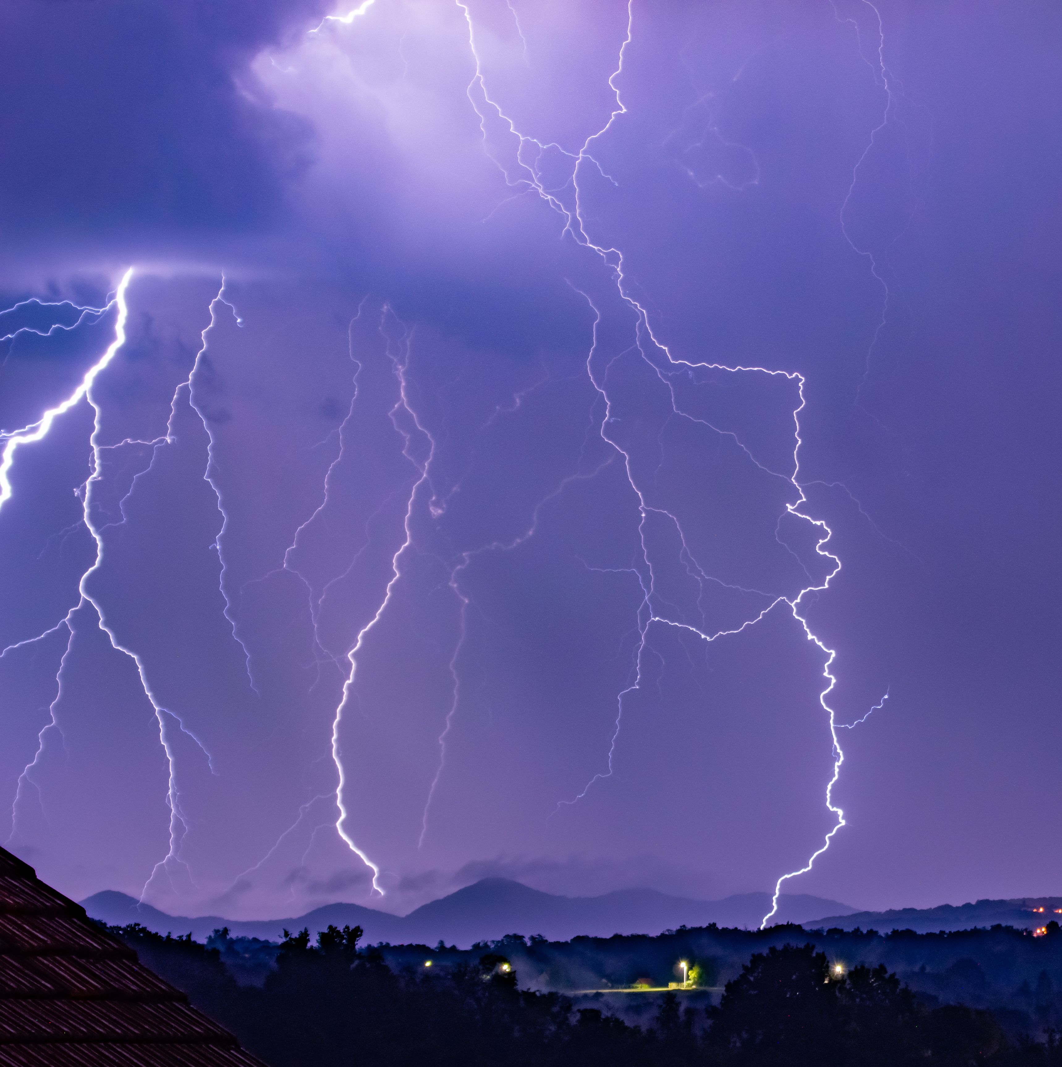 A breathtaking view of a thunderstorm with vivid lightning strikes over mountains at night.