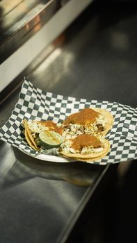 Three delicious tacos with toppings served on a checkered napkin in a restaurant setting.