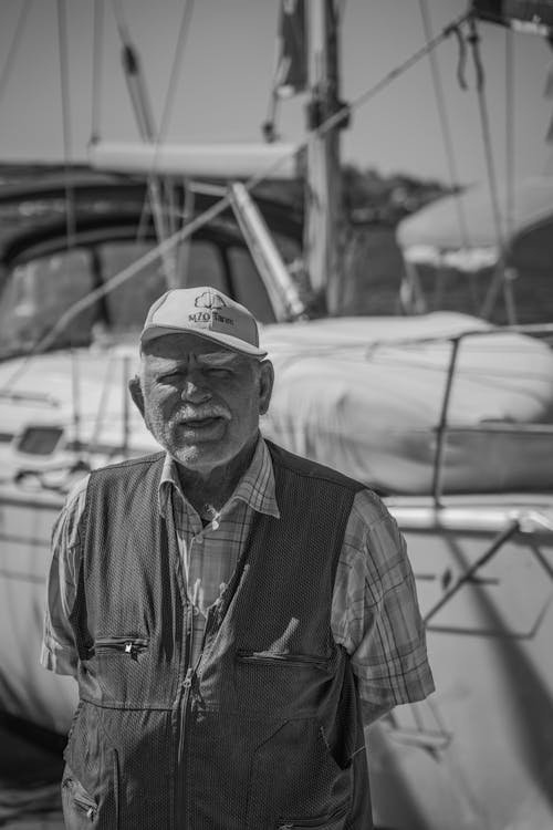 Elderly Man Standing Beside a Sailboat