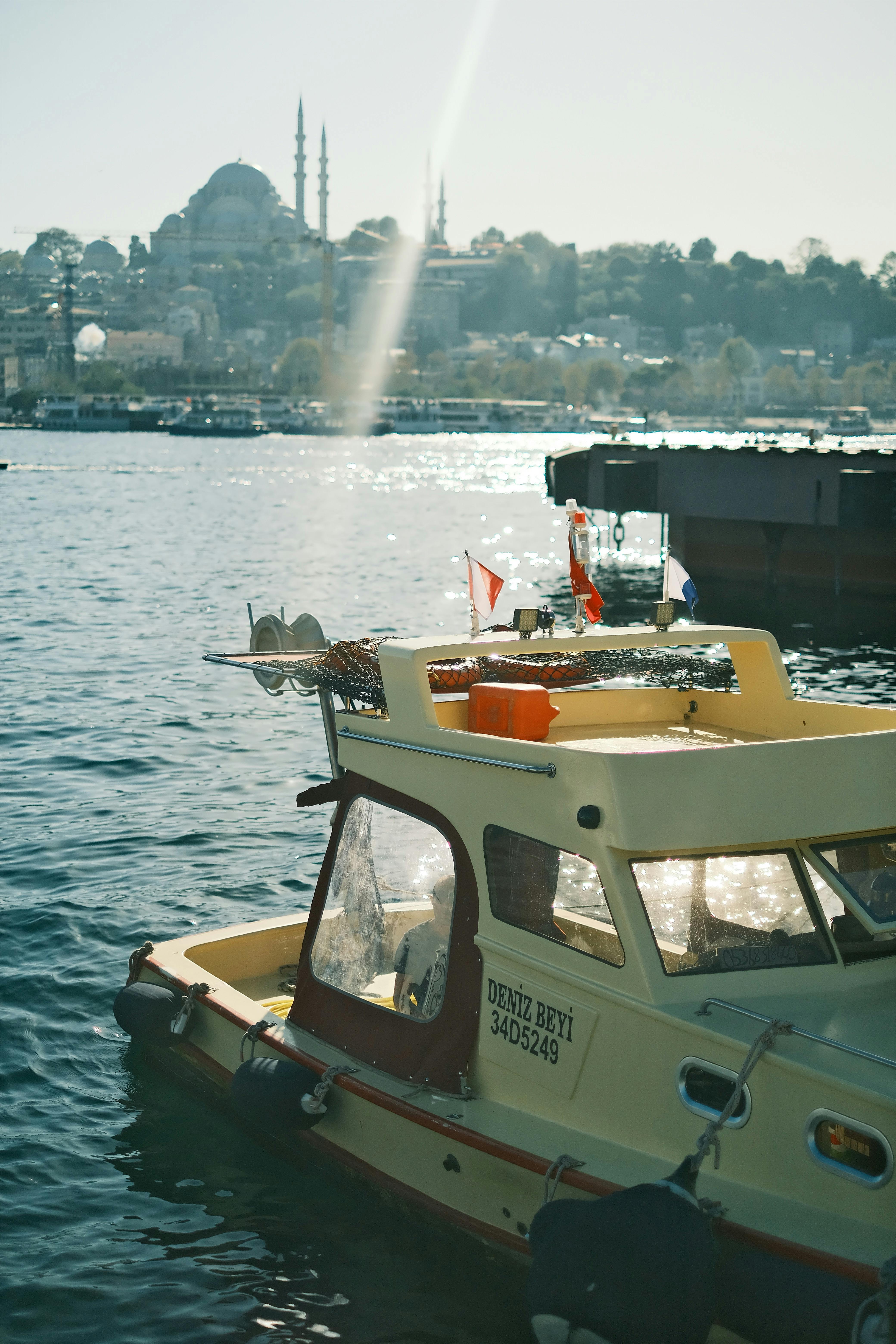 A peaceful scene of a boat on the water with an Istanbul skyline backdrop, featuring a historic mosque.