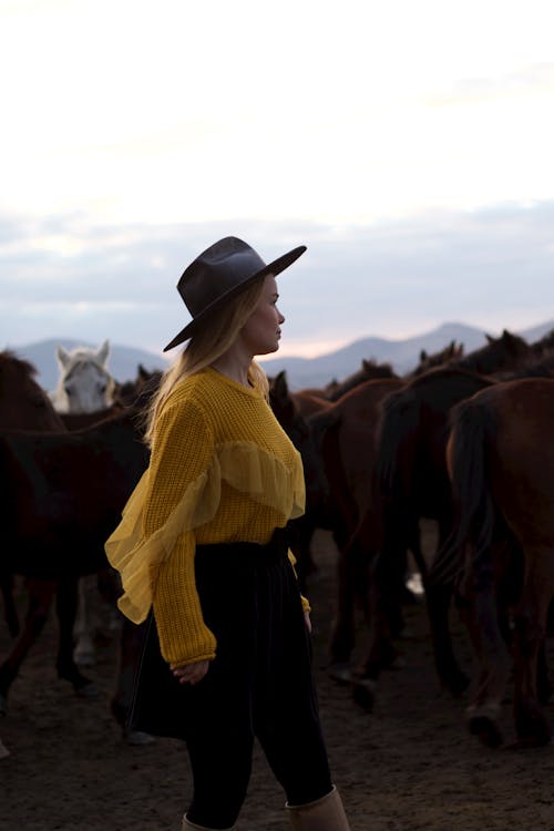 Blonde Woman in Hat in Herd of Horses