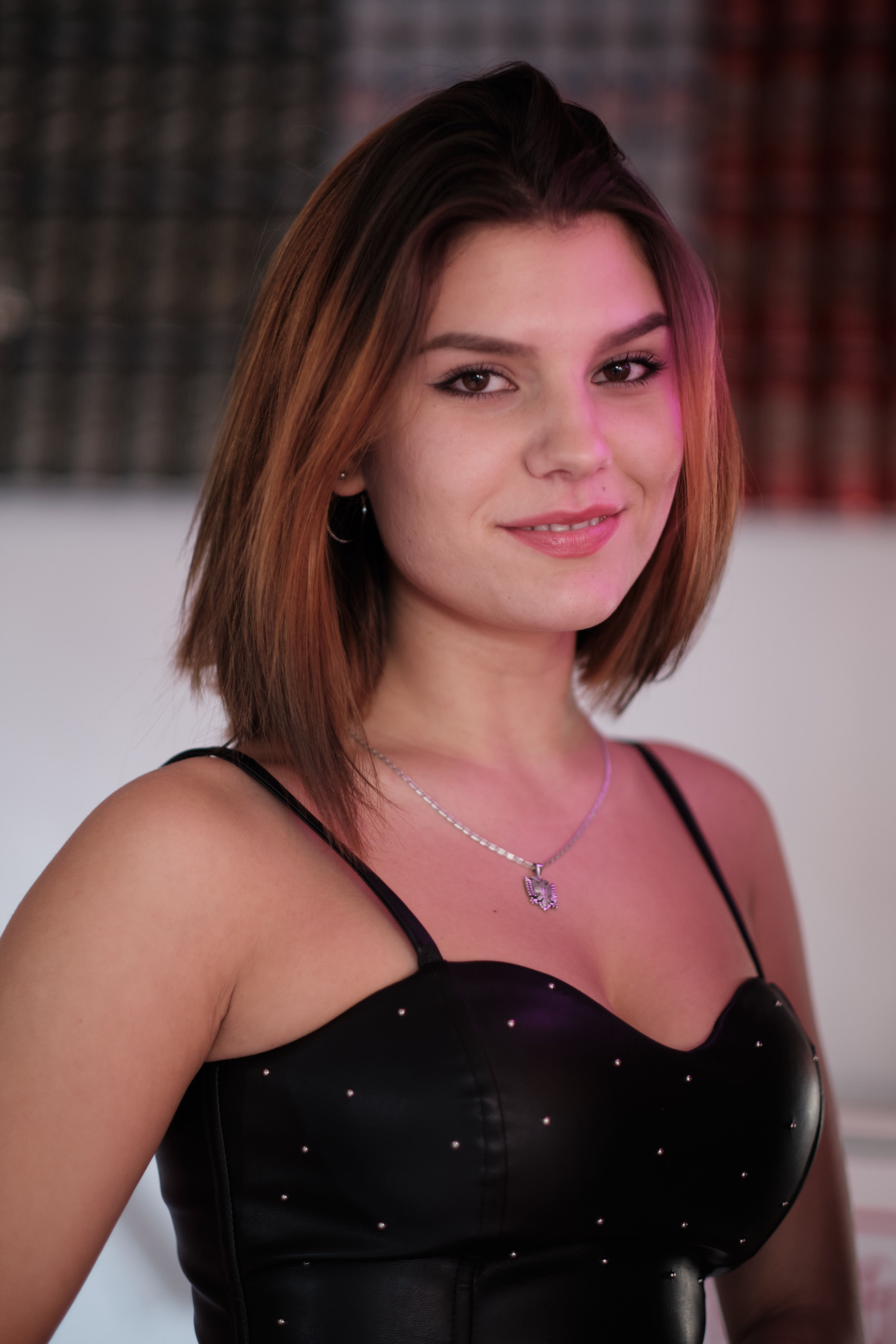 Charming portrait of a confident woman in a sleeveless black top indoors, showcasing style and elegance.