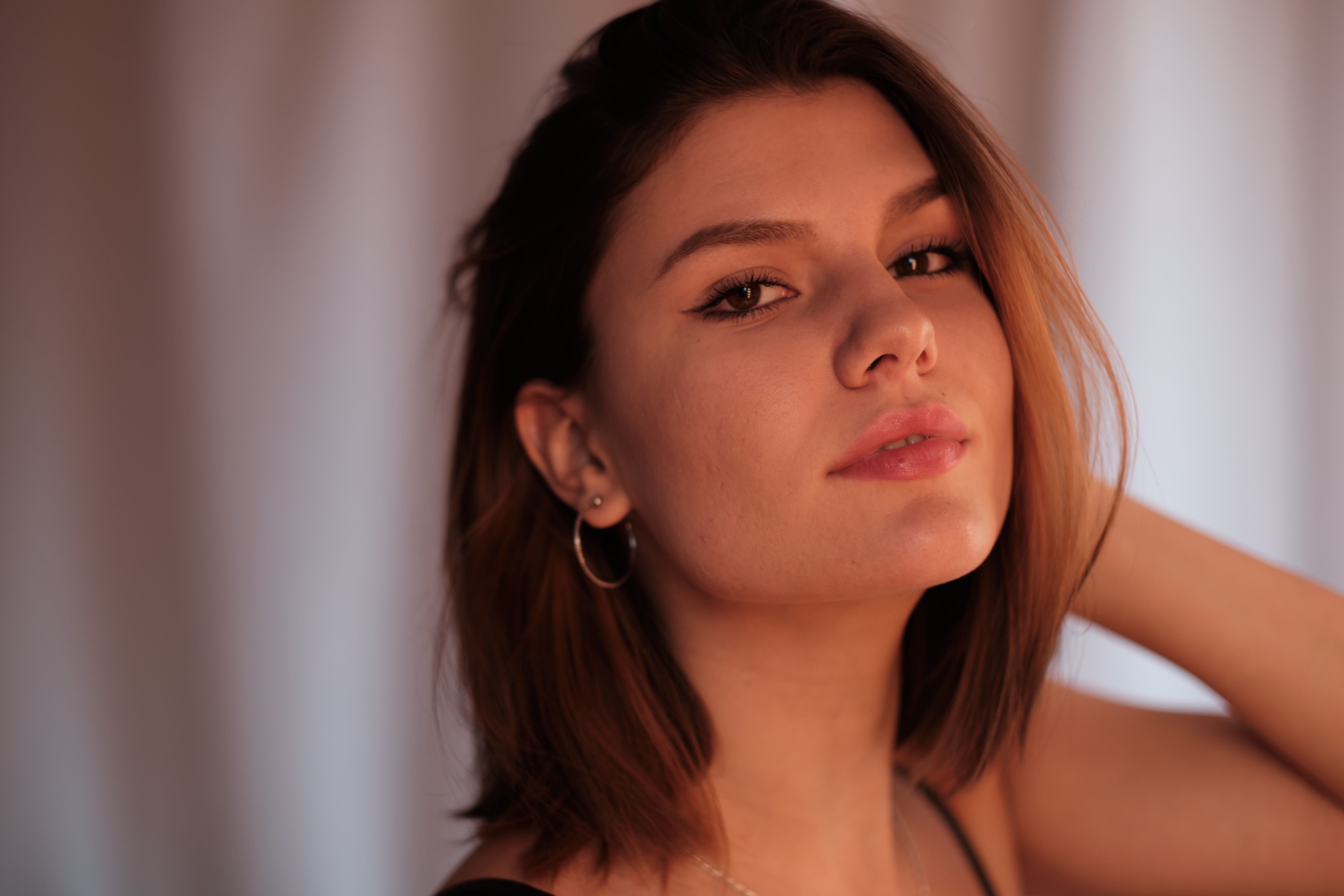 Close-up portrait of a young woman with natural makeup and soft lighting, showcasing elegance.