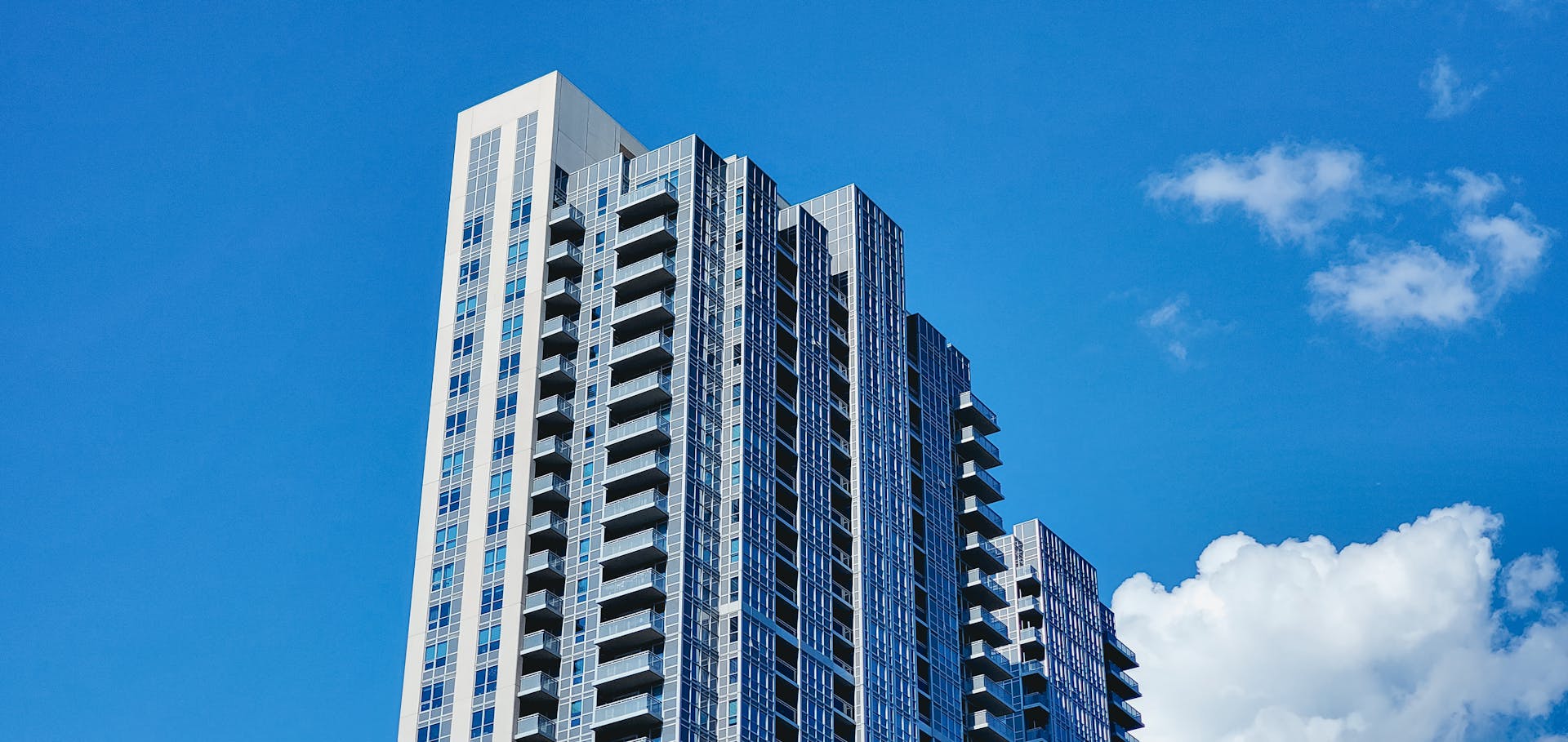 Tall modern high-rise building set against a vibrant clear blue sky, showcasing contemporary architecture.