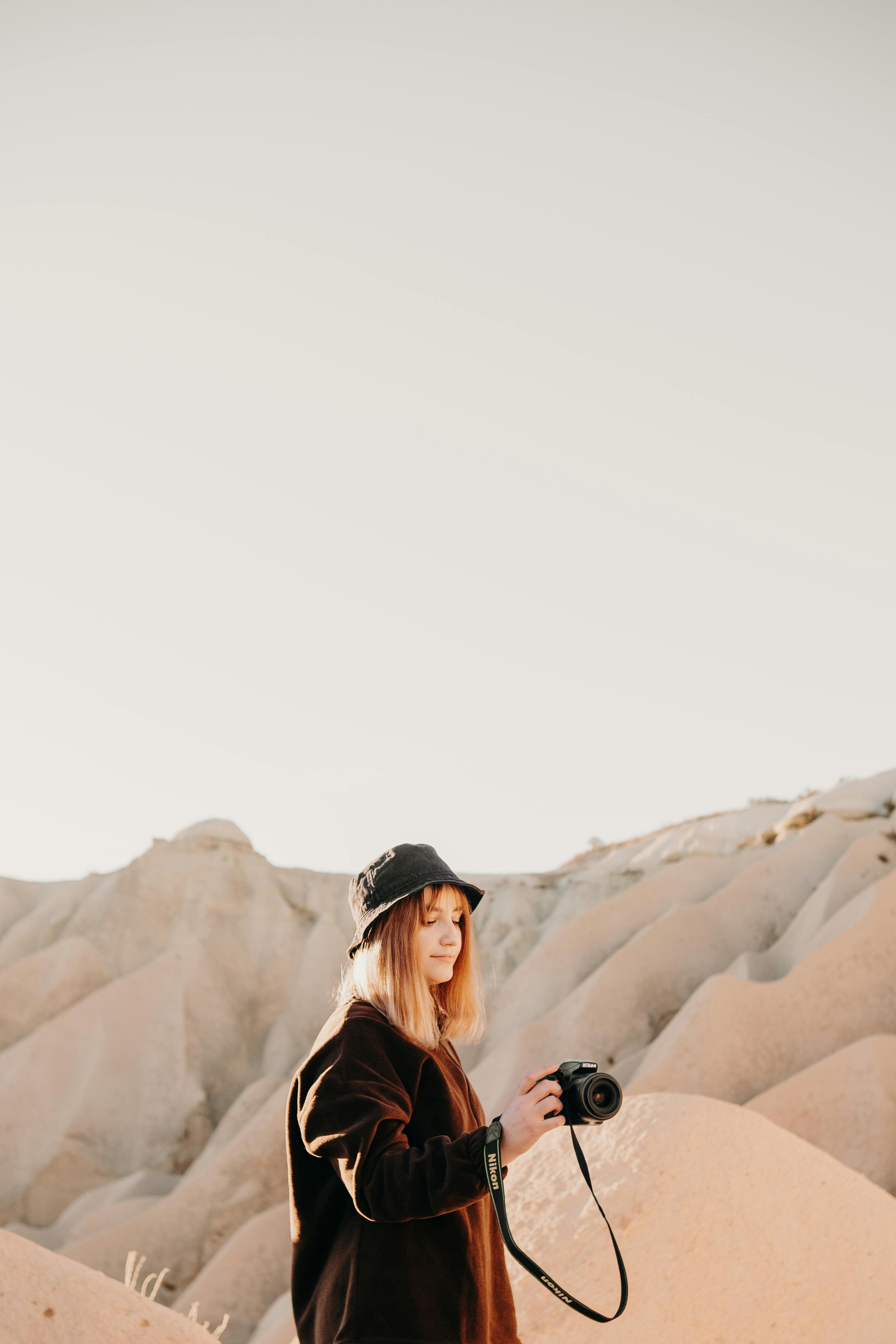 woman wearing a hat photographing in a rocky landscape