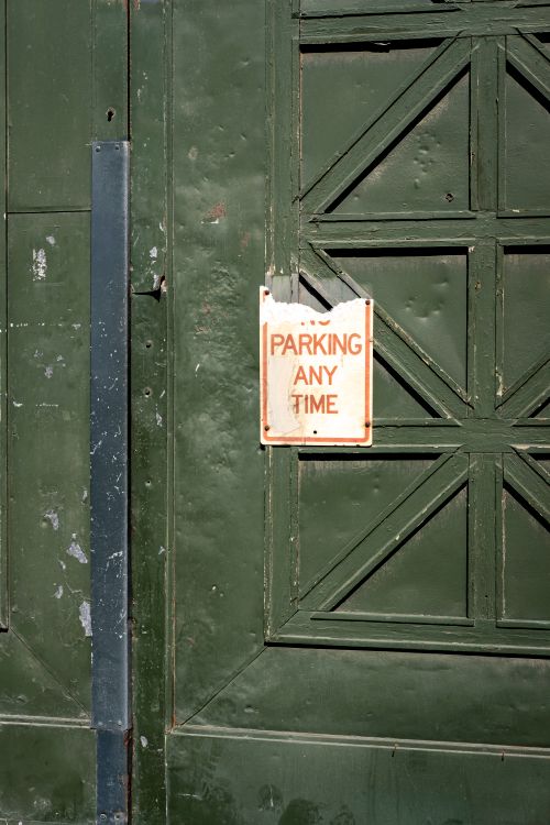 Free Close-up of a faded 'Parking Any Time' sign on a distressed green door. Stock Photo