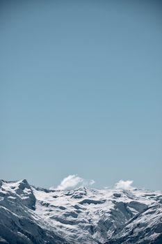 Breathtaking snow-covered mountains under a clear blue sky, showcasing winter's serene beauty.