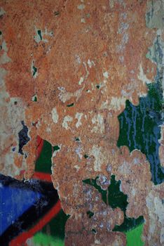 Close-up of a rusty, corroded wall with vibrant peeling paint textures and abstract colors.