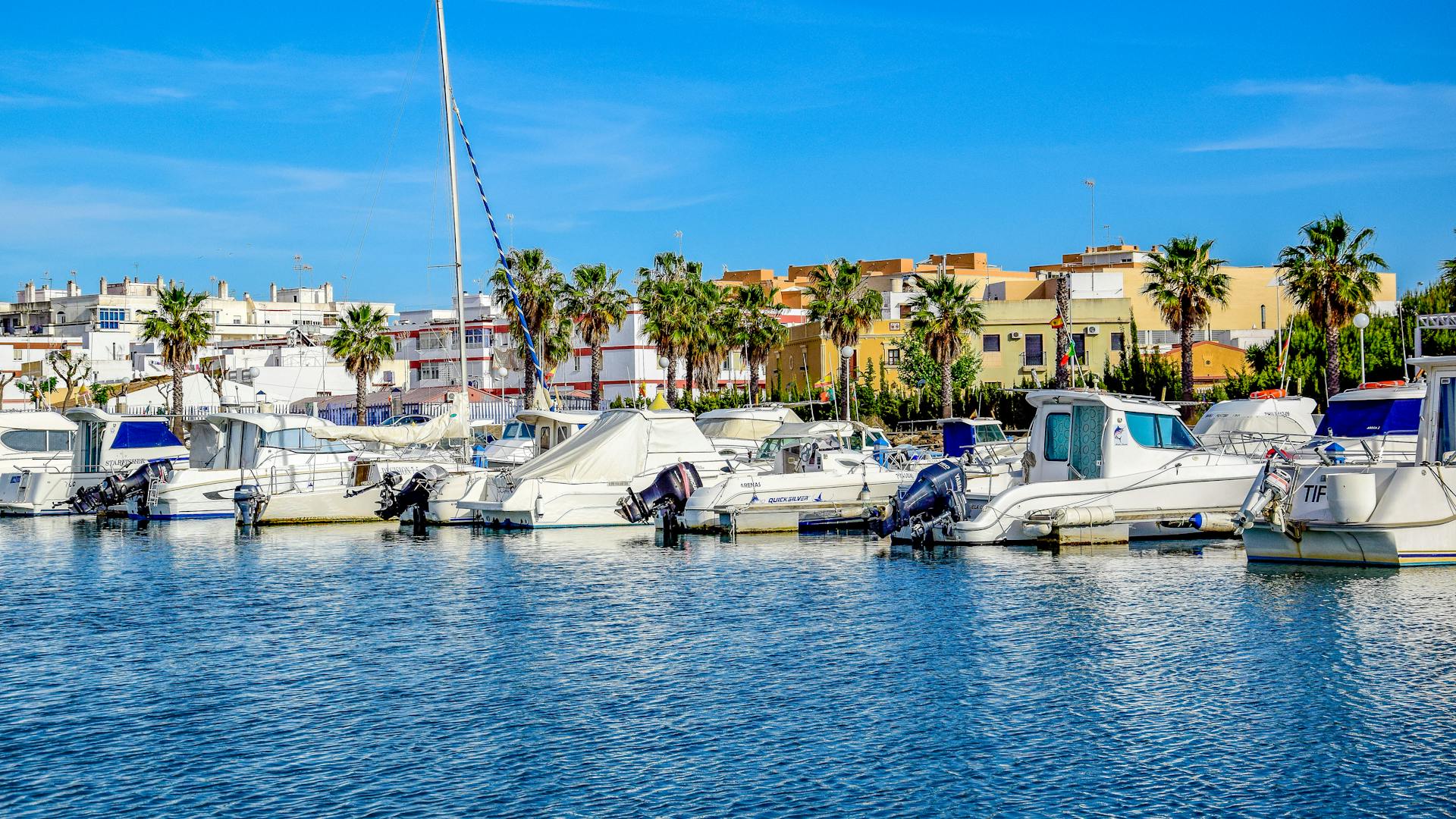 Colorful boats docked in Isla Cristina harbor on a sunny day.