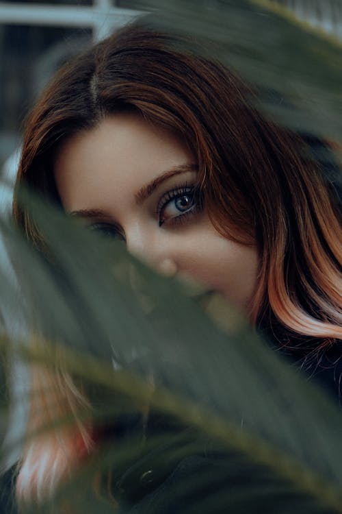 Woman with her Face Behind a Palm Leaf