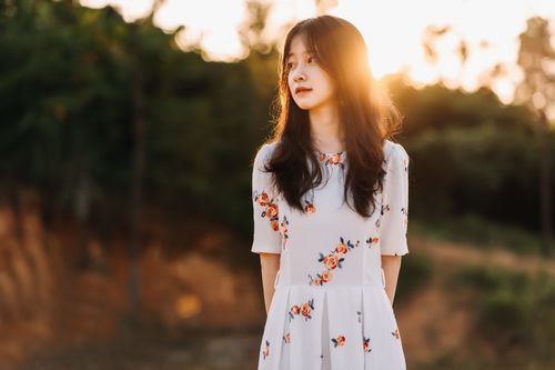 Free Beautiful portrait of an Asian woman in a floral dress, captured during sunset outdoors. Stock Photo