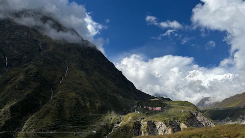 A Green Grass Field on Mountain Under the Blue Sky and White Clouds