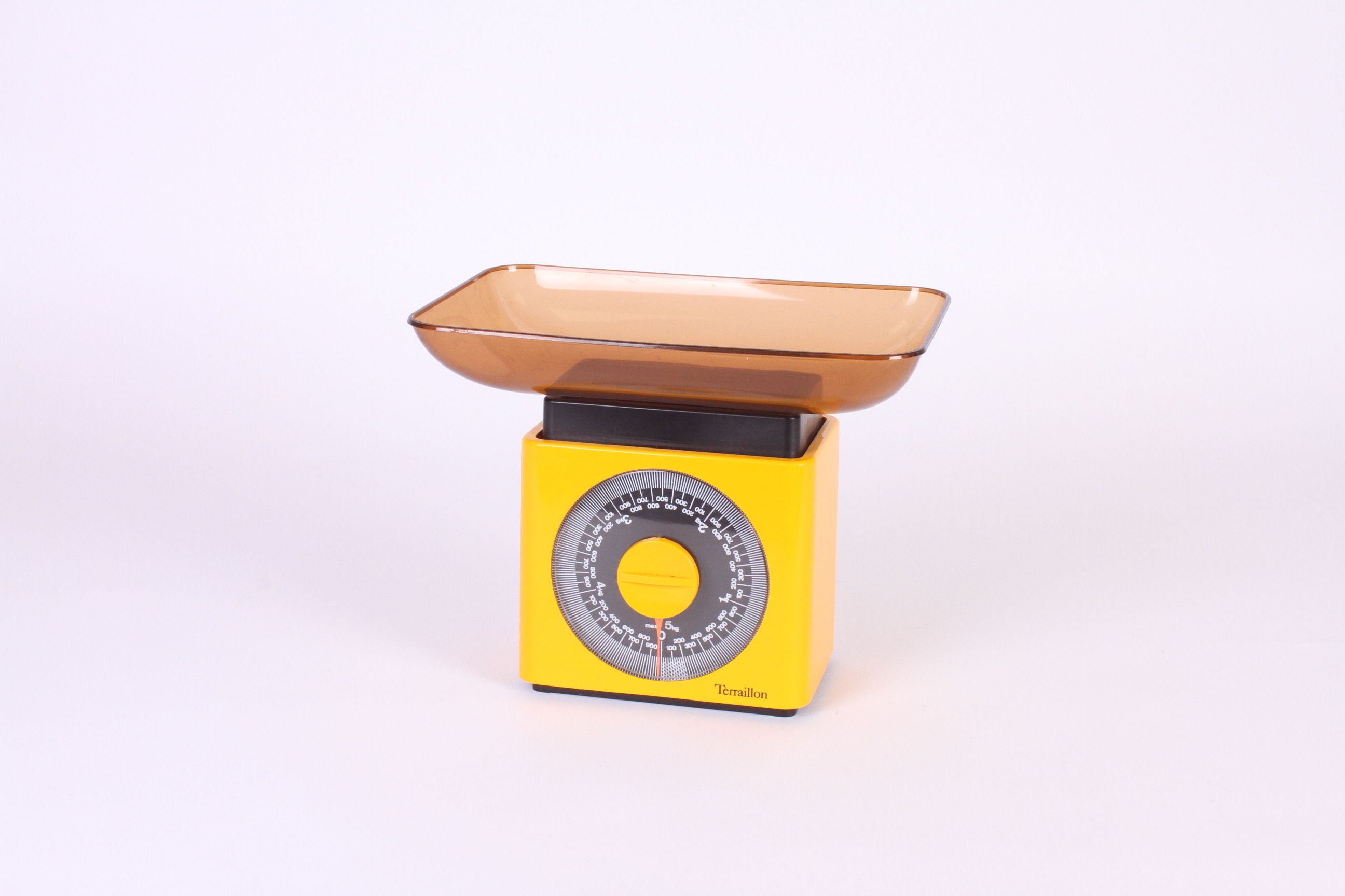 Vintage yellow kitchen scale with brown plastic tray on a white surface.