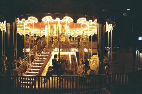 Free A magical illuminated carousel glowing at night in an amusement park setting. Stock Photo