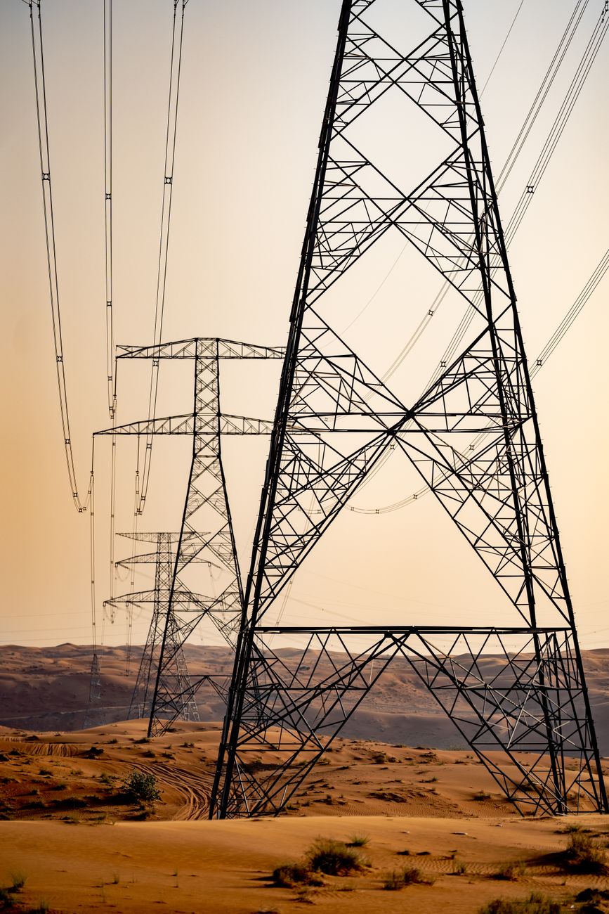 Power transmission lines crossing desert terrain in the Gulf, illustrating the electricity backbone behind regional data-center projects.