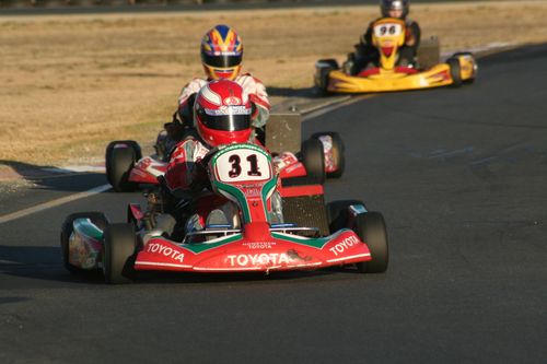 Free Three competitive go-kart racers on an outdoor track, showcasing intense motorsport action. Stock Photo