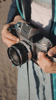 Close-up of a person holding a vintage camera outdoors, emphasizing photography passion.