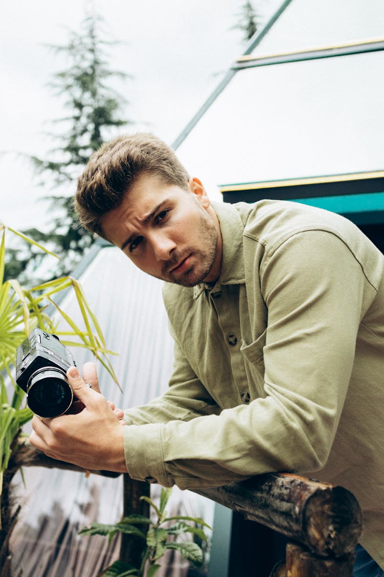 Man In Green Dress Shirt Holding Black Camera