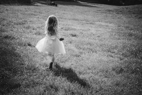 Black and White Photo of a Girl Running in the Field