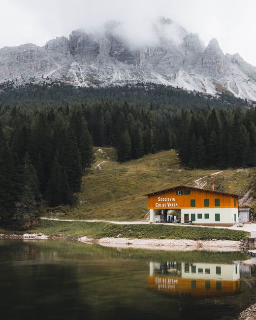 Tranquil lake and mountain view in Misurina, Veneto, Italy, with cabin reflection.