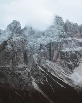 Breathtaking view of the Dolomite mountains in winter, showcasing rugged peaks and dramatic clouds.