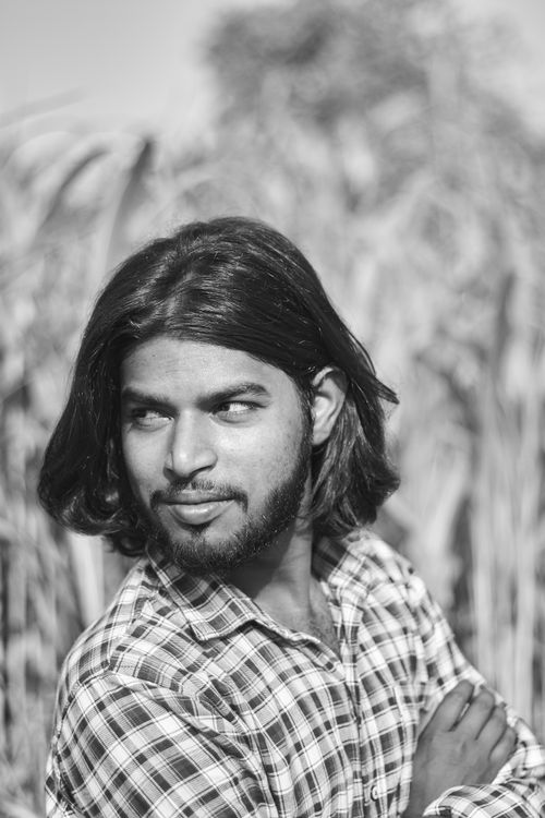 Free Grayscale portrait of a bearded man in a plaid shirt with natural outdoor background. Stock Photo