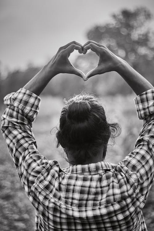 Grayscale Photo of Man in Plaid Long Sleeves Doing Love Heart Shape With Hands